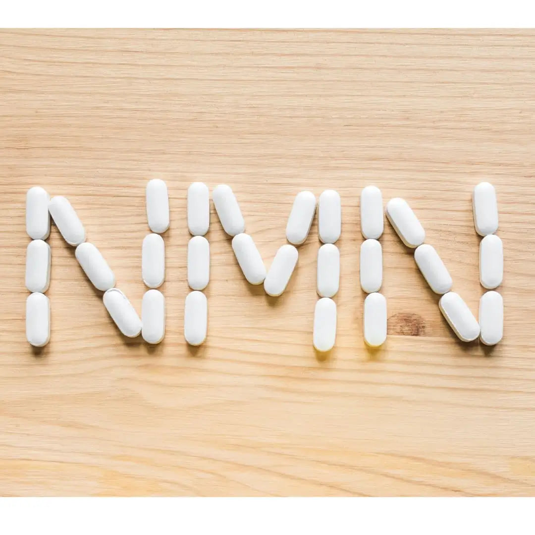 White pills spelling "NMN" on a wooden surface.
