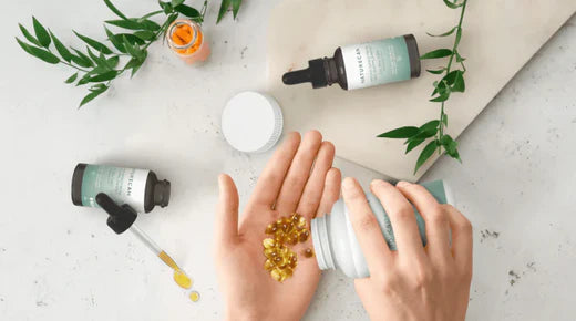 Hand holding CBD Capsules and in the background CBD products on the table