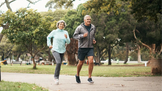 Older woman and man jogging through park in sportswear