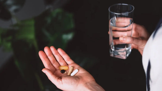 Hand with Resveratrol on it next to glass of water