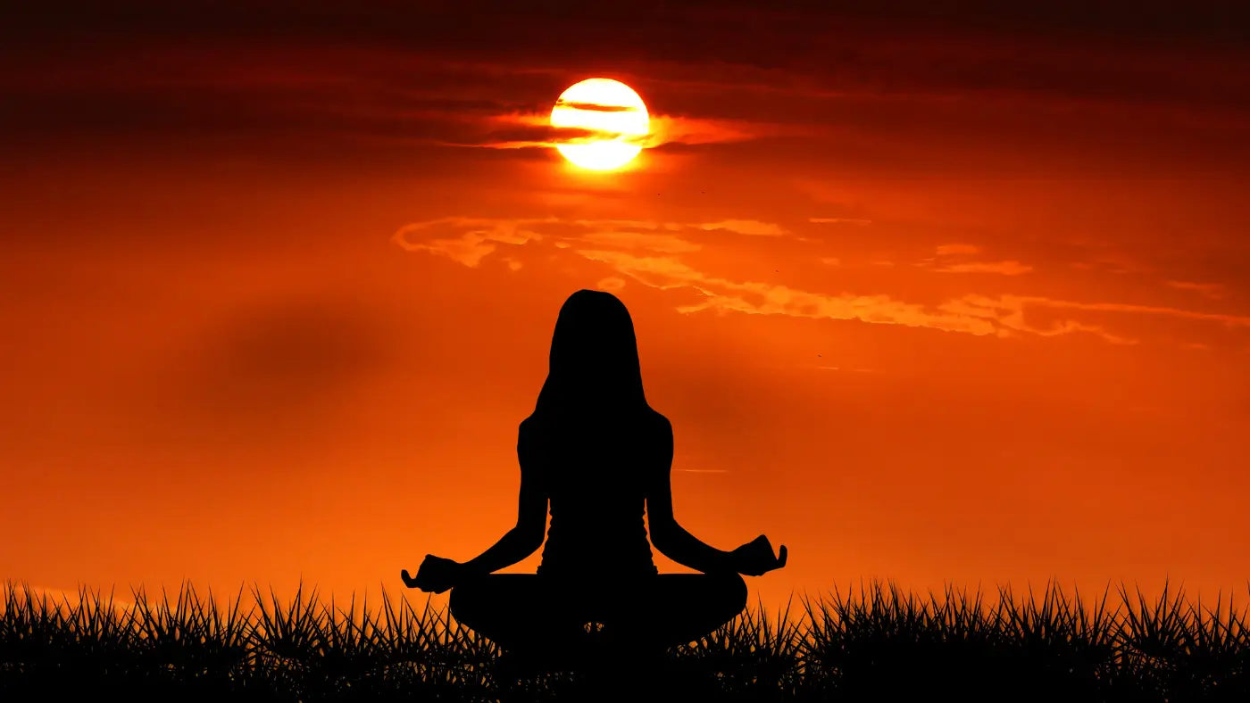 woman meditating at sunset
