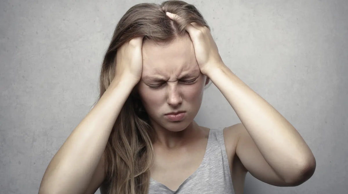 A woman holding her head in pain, suffering from a headache