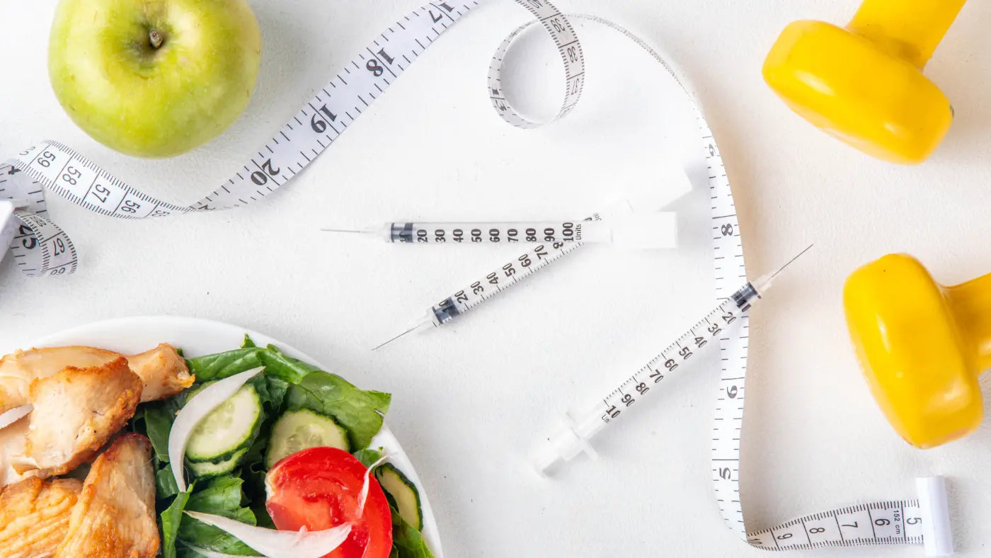 a health and fitness-themed setup, featuring syringes, a green apple, a fresh salad with chicken, a white measuring tape