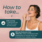 Instructional graphic showing a woman applying a white capsule to her mouth with text explaining daily serving and dosage of a hyaluronic acid and zinc supplement on a soft pink background.
