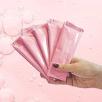 Hand holding pink Naturecan collagen peptide sticks with a bubble background.