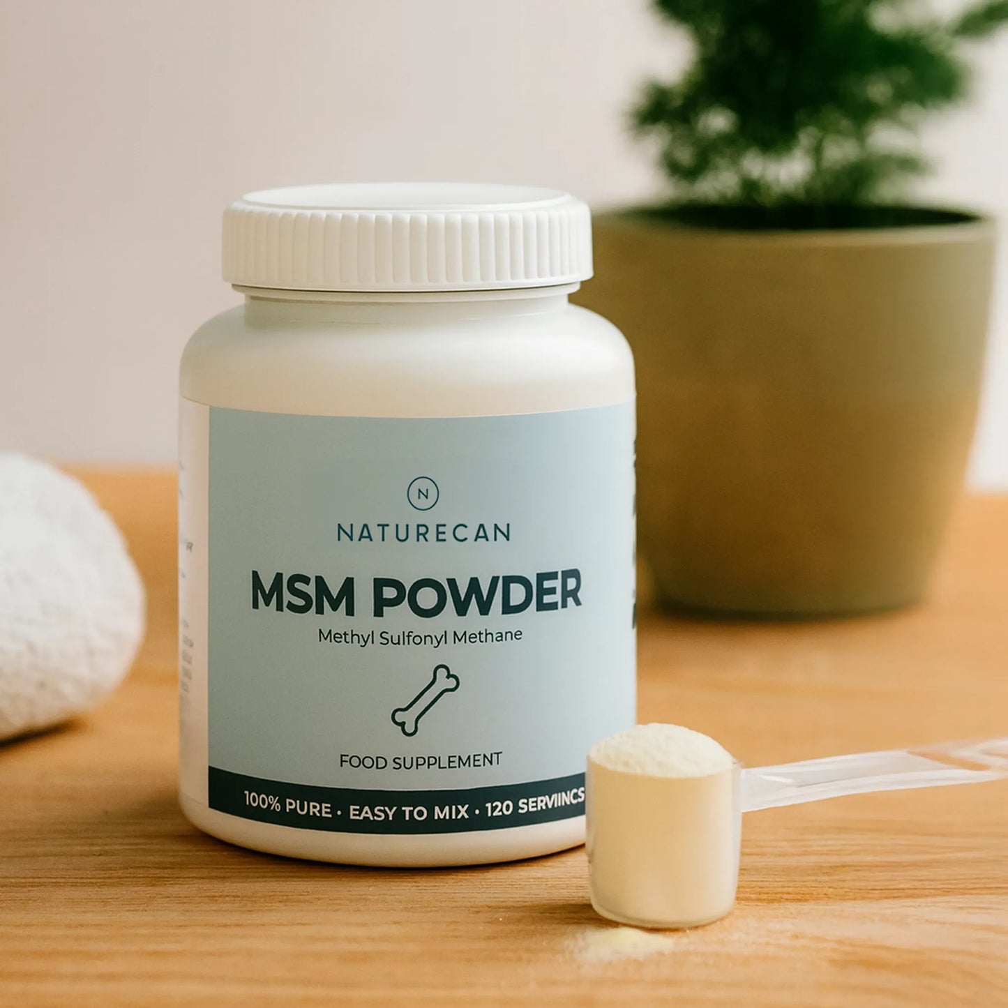Naturecan MSM Powder supplement bottle on a wooden surface with a plant in the background