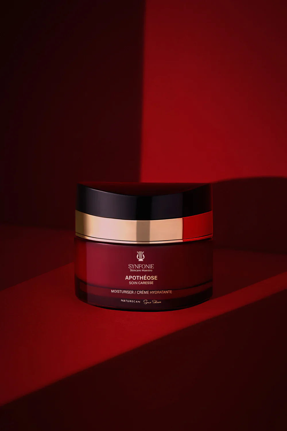 Cosmetic jar with black, red, and gold design on a red background